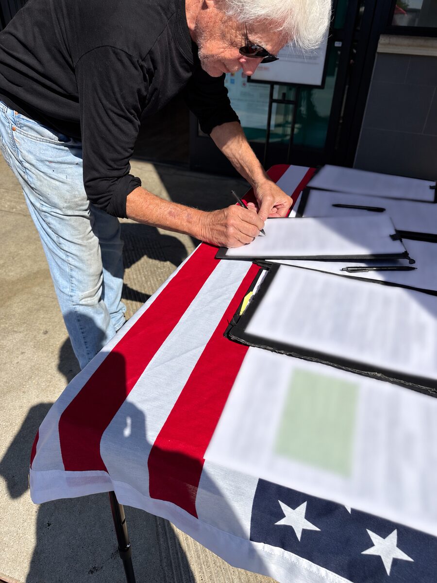 A voter signing a form at an outreach table